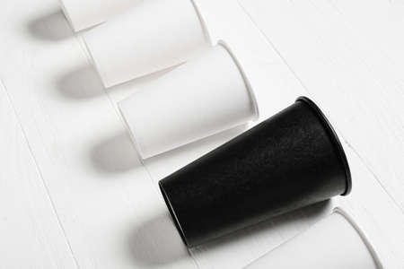 Black cup among white ones on wooden background. concept of racismの写真素材