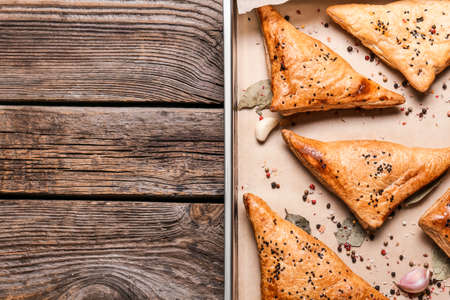 Baking tray with tasty Uzbek samsa on wooden background