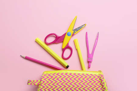 Pencil case with colorful stationery on pink background