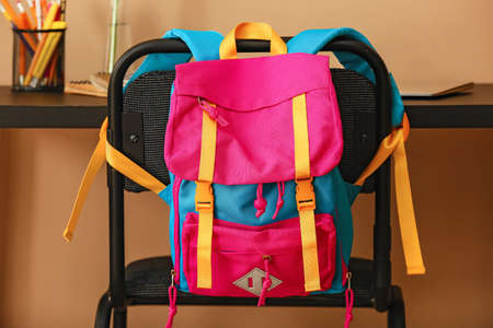 Stylish backpack hanging on chair in roomの写真素材