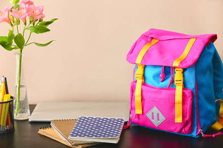 Stylish backpack, notebooks and vase with flowers on tableの写真素材