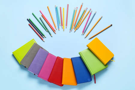 Set of notebooks and pencils on color background