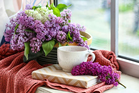 Lilac flowers with cup of tea on windowsillの写真素材