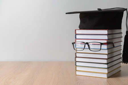 Creative composition with books, eyeglasses and graduation hat on tableの写真素材
