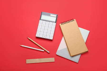 Notebooks, calculator, pencils and ruler on red background