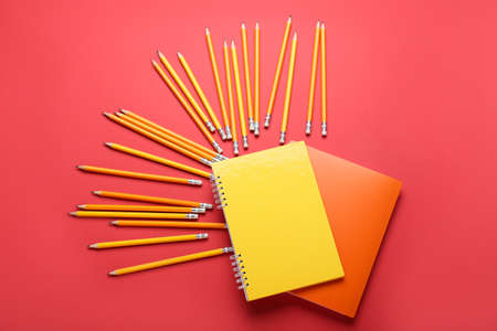 Notebooks and ordinary pencils on red background