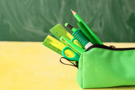 Green pencil case with different stationery on table, closeupの写真素材
