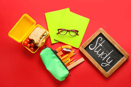 Chalkboard with word STUDY, stationery, eyeglasses and food on red backgroundの写真素材