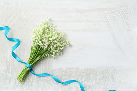 Beautiful lily-of-the-valley flowers and ribbon on light backgroundの写真素材