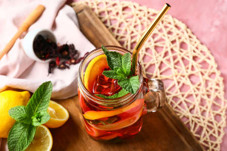 Mason jar of tasty ice tea with fruits on color backgroundの写真素材