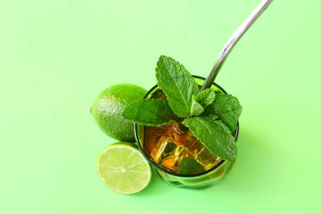Glass of tasty ice tea with lime on color background