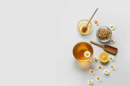 Composition with tasty chamomile tea, flowers and honey on gray backgroundの写真素材
