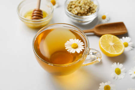 Composition with tasty chamomile tea, flowers and honey on gray backgroundの写真素材