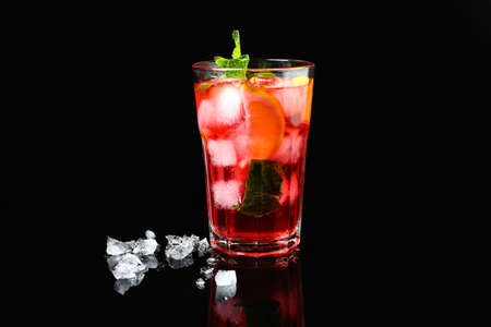 Glass of tasty ice tea with lemon on dark background