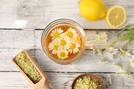Composition with tasty chamomile tea, flowers and lemon on light wooden backgroundの写真素材