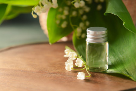 Bottle with essential oil and lily-of-the-valley flowers on wooden backgroundの写真素材