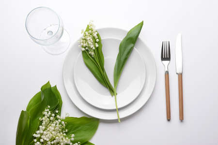 Beautiful table setting with lily-of-the-valley flowers on light backgroundの写真素材