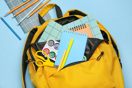 Stylish school backpack with stationery on color background, closeup