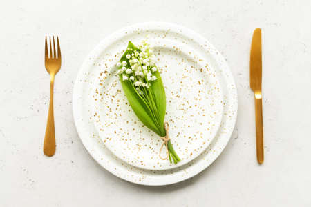 Beautiful table setting with lily-of-the-valley flowers on light background