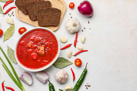 Bowl with tasty borscht and ingredients on light background