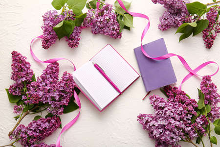 Beautiful lilac flowers, pen and notebooks on light backgroundの写真素材