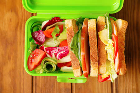 Lunch box with tasty sandwiches and vegetables on wooden background, closeupの写真素材