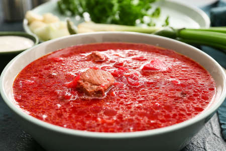 Bowl of tasty borscht on table, closeup