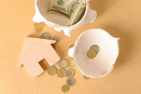 Wooden house with piggy bank and money on beige backgroundの写真素材