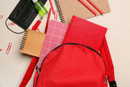 School backpack and stationery on light background