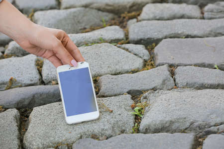 Woman with damaged mobile phone outdoors, closeup