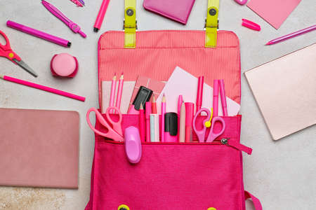 School backpack and stationery on light background