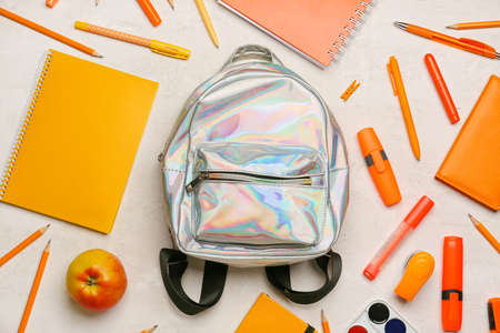 School backpack and stationery on light background