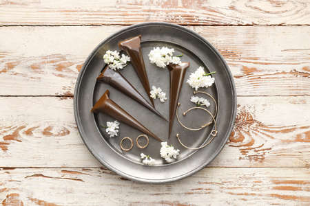 Henna paints and jewelry in tray on wooden background