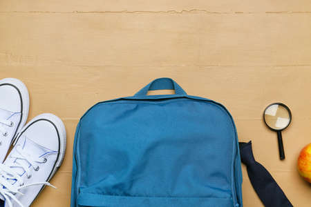 School backpack, shoes and magnifying glass on color wooden backgroundの写真素材