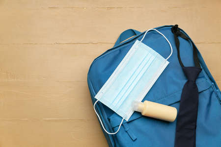 School backpack, medical mask and antiseptic on color wooden backgroundの写真素材