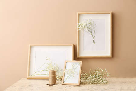 Photo frames and beautiful gypsophila flowers on table