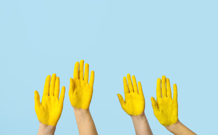 Many hands with painted yellow palms on blue backgroundの写真素材