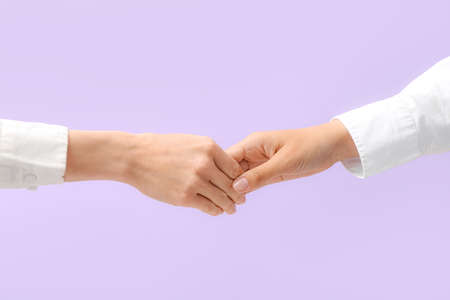 Women holding hands together on color background