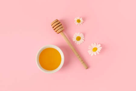 Bowl of sweet honey and chamomile flowers on pink backgroundの写真素材
