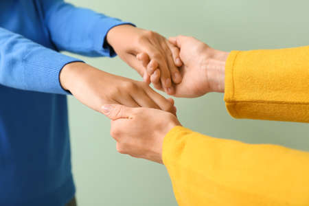 Women holding hands on light background, closeupの写真素材
