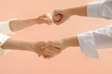 Businesswomen holding hands together on color backgroundの写真素材
