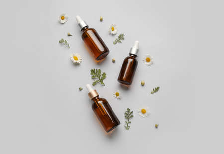Composition with bottles of essential oil and chamomile flowers on gray backgroundの写真素材