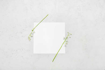 Beautiful lily-of-the-valley flowers and blank card on light background