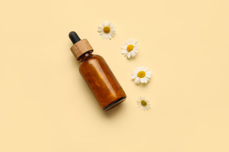 Bottle of chamomile essential oil on color backgroundの写真素材