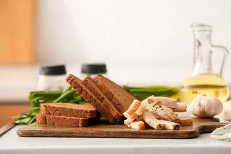 Wooden board with delicious lard and bread on table in kitchen