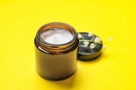 Jar of cosmetic product and lily-of-the-valley flowers on color backgroundの写真素材