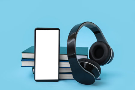 Modern mobile phone, headphones and books on blue backgroundの写真素材