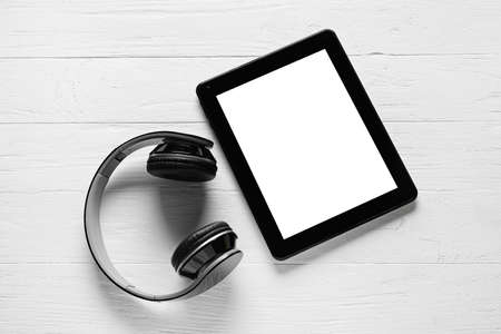 Modern tablet computer and headphones on light wooden backgroundの写真素材