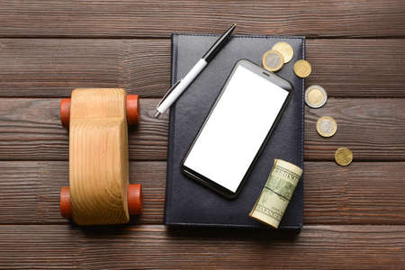 Car with mobile phone, money and stationery on wooden backgroundの写真素材