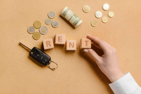 Woman with word RENT, car key and money on beige backgroundの写真素材